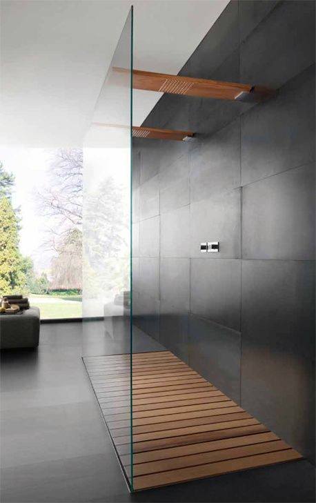 Walk-in shower with glass divider, wooden floor slats, and modern black tiled walls.