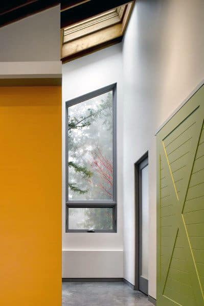 Modern interior with yellow and green walls, skylight, and large window with outdoor view.