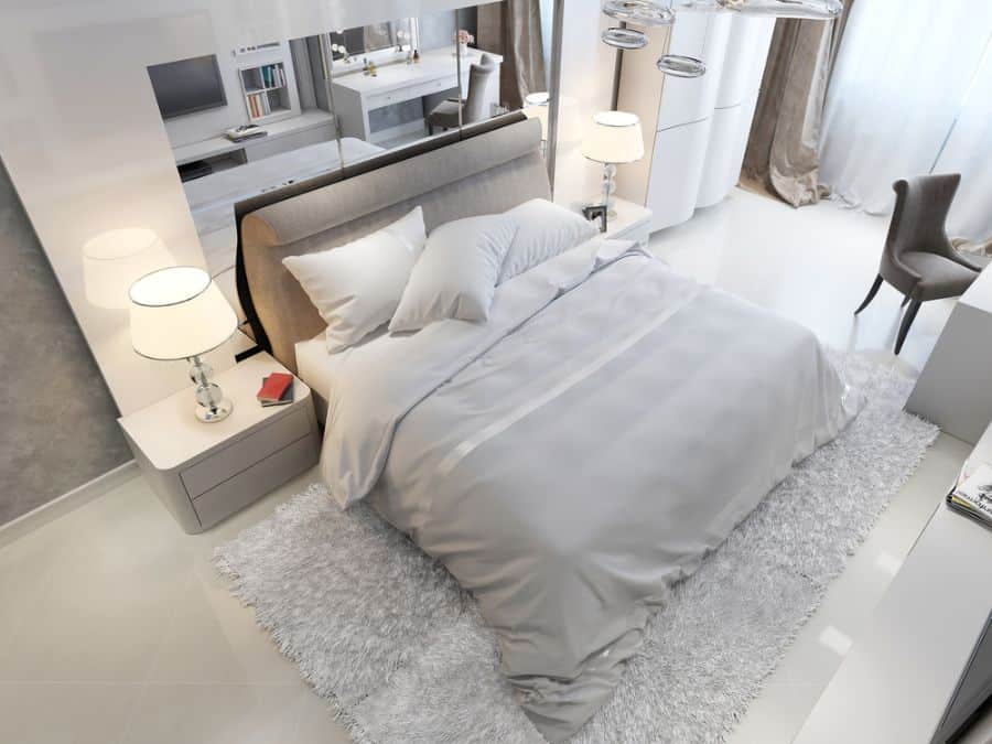 Modern bedroom with a neatly made white bed, bedside tables with lamps, and a shaggy rug on the floor