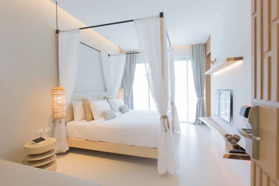 White canopy bed with soft lighting and modern furnishings creates a bright, inviting bedroom