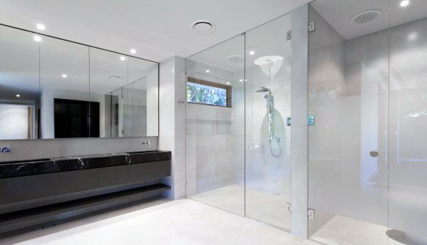 Modern bathroom with glass shower, large mirror, and dark vanity on sleek floor