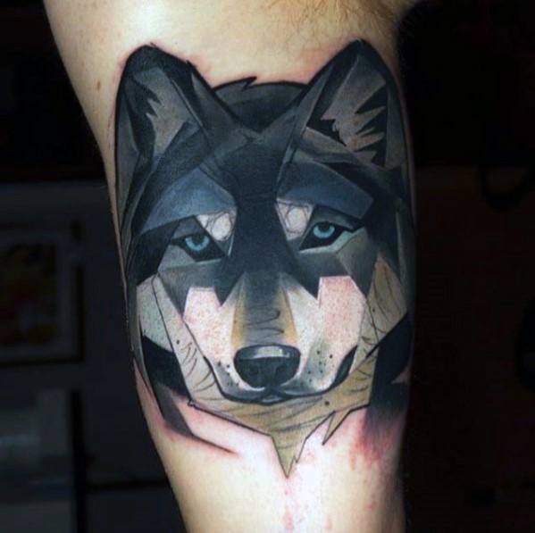 Geometric wolf tattoo with bold black outlines, sharp angular shapes, and muted tones for a modern, stylized upper arm design.