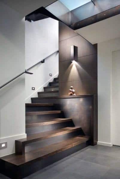 Modern, minimalist staircase with dark wood steps and soft lighting on a textured staircase wall