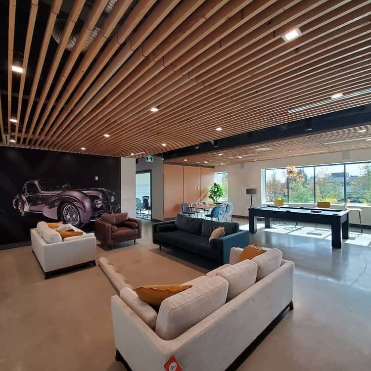A modern office space featuring a stylish wooden floating ceiling with integrated lighting, contemporary seating, and a sleek design, creating a spacious and inviting environment