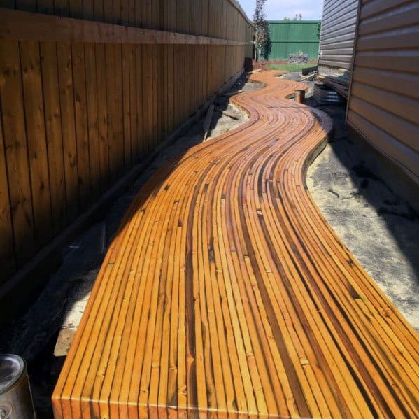 Winding wooden walkway between two buildings under a clear sky