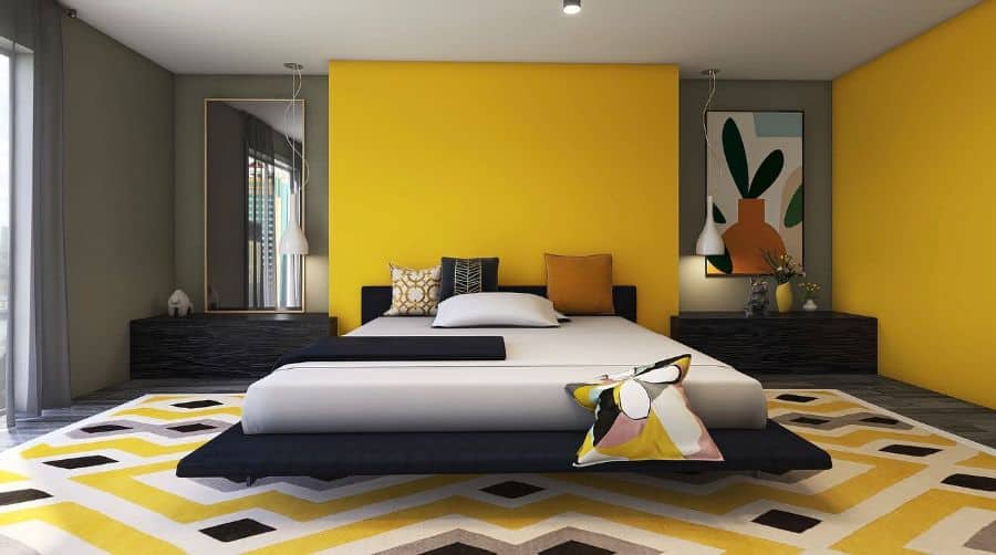 Modern bedroom with a bold yellow accent wall, geometric rug, and black furniture; abstract art enhances the space
