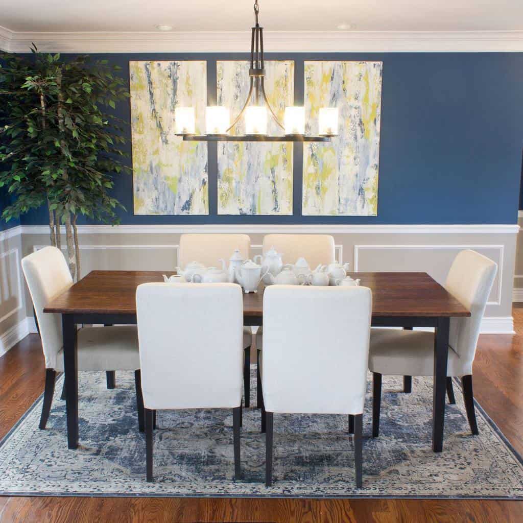 two tone blue and gray dining room walls brown table white chairs teapots chandelier abstract wall art