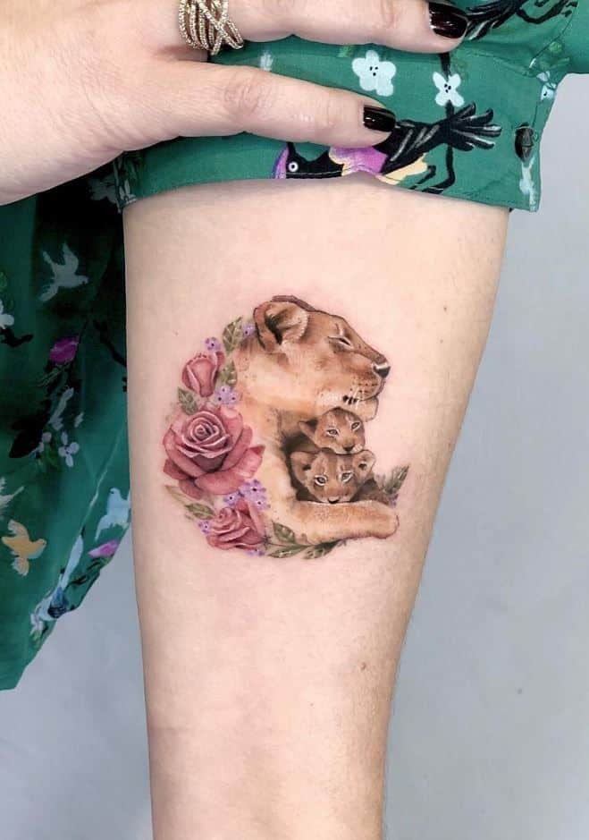 Realistic lioness tattoo on the thigh, featuring a mother lion with cubs, surrounded by roses for a soft, nurturing design.