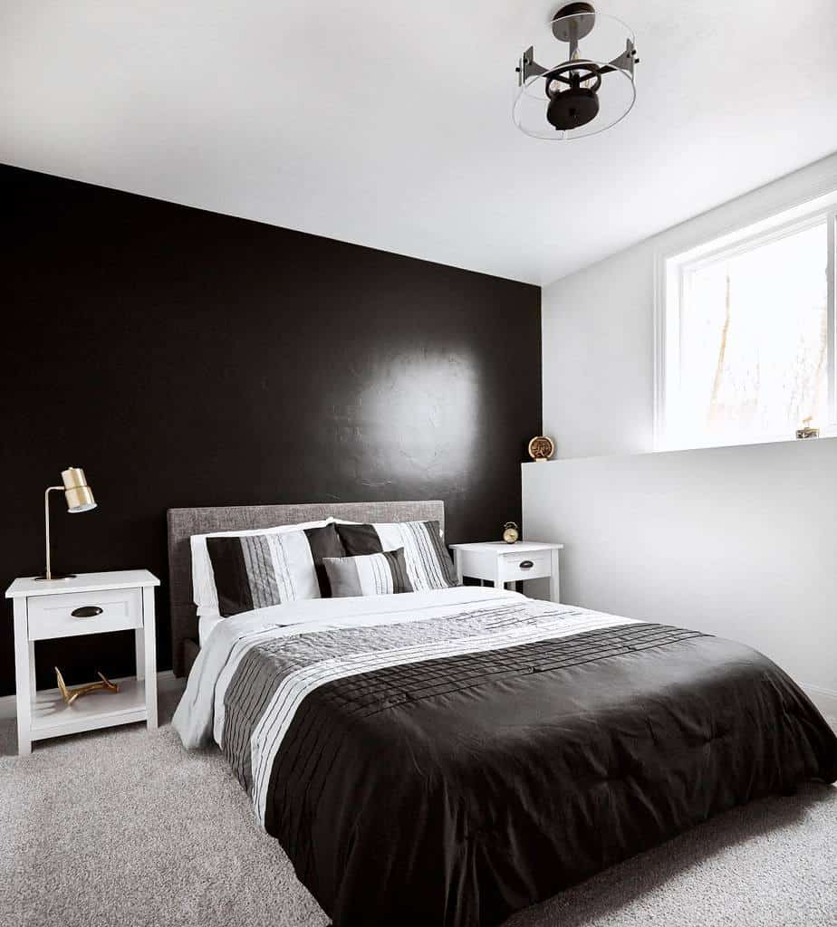 Monochrome bedroom with a black feature wall, white bedside tables, and striped bedding.