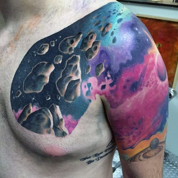 Colorful space-themed tattoo with asteroids and nebula on a person's upper chest
