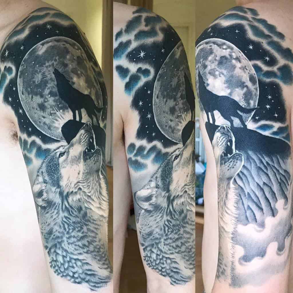 A captivating tattoo of a wolf howling at a radiant full moon, with ethereal clouds and twinkling stars forming the mystical backdrop on an upper arm