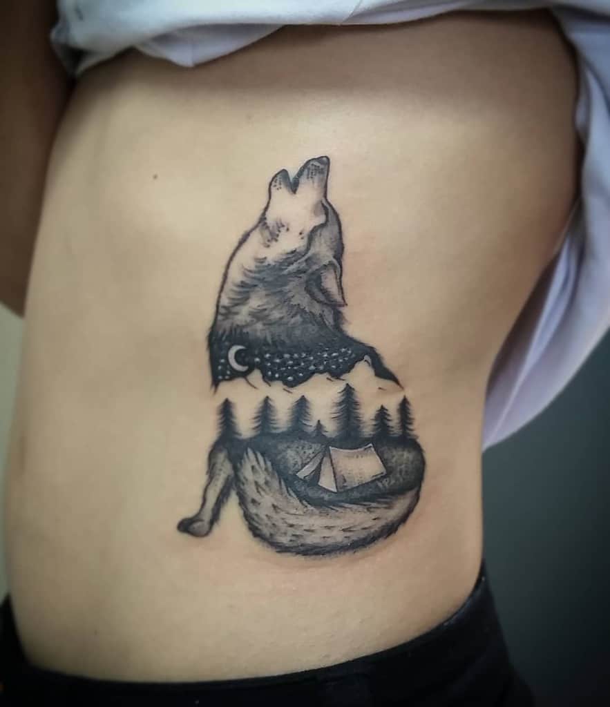A mesmerizing tattoo of a howling wolf, beautifully intertwined with a night sky, silhouetted trees, and a cozy tent on the side