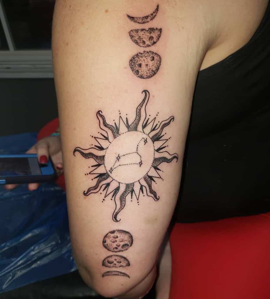 Leo zodiac tattoo on the upper arm with a glowing sun and moon cycle, blending astrology with cosmic symbolism.