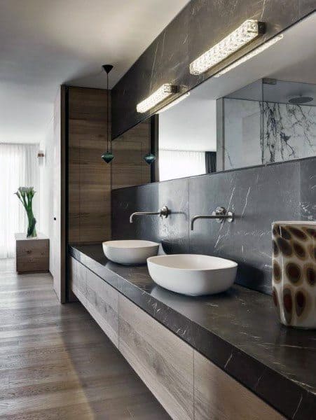 Modern bathroom with dual sinks, large mirror, pendant lights, and wooden cabinetry