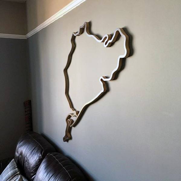 Minimalist wall art featuring a motorbike circuit outline above a leather couch.