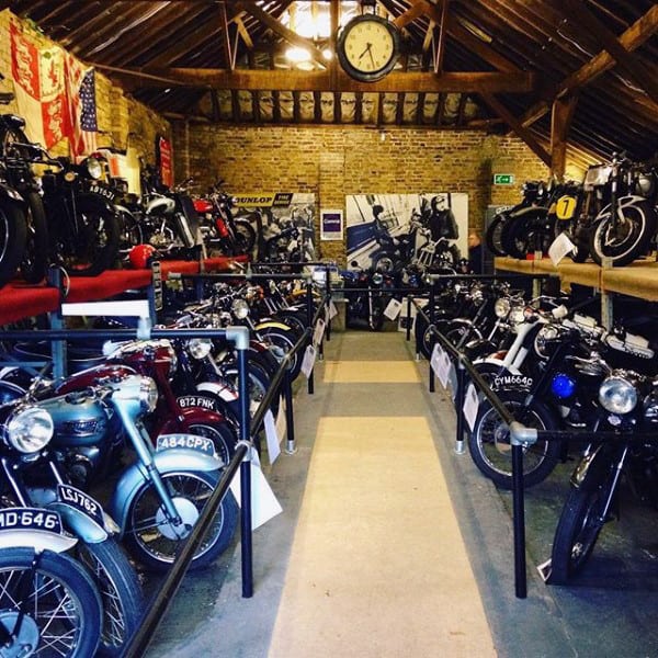A rustic garage filled with vintage motorcycles, exposed brick walls, and a wooden beam ceiling for a timeless charm.