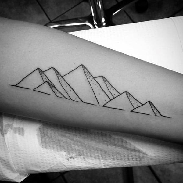 Minimalist mountain range tattoo on a forearm