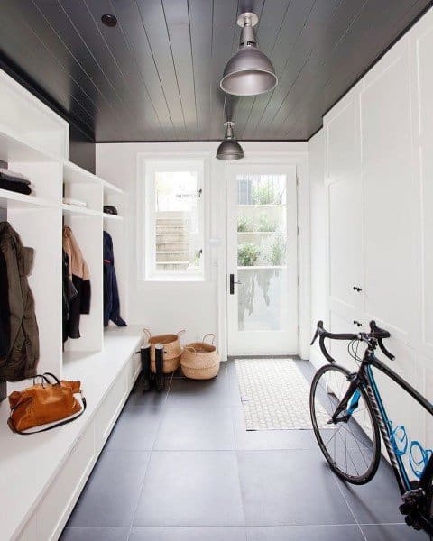 large modern mudroom with black floor tiles and seating