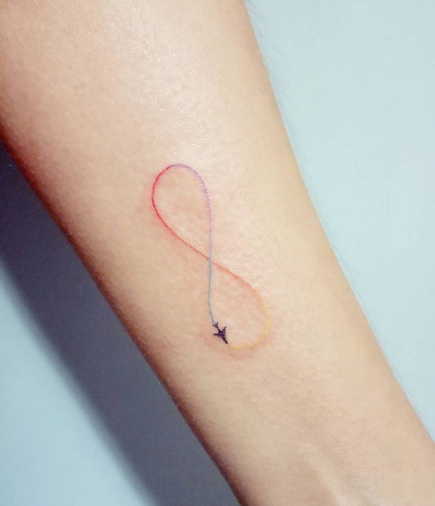 A colorful infinity tattoo with a small airplane flying along the loop, symbolizing endless travel or freedom.