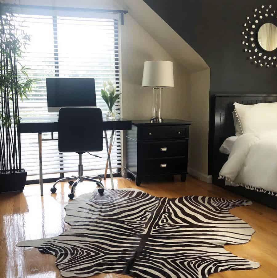 Spacious bedroom with black desk, zebra print rug, and modern decor accents.