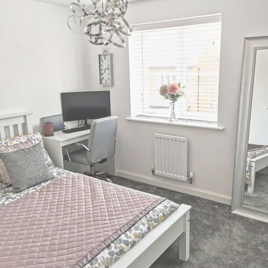 Bright bedroom with small white desk, computer setup, and large mirror.