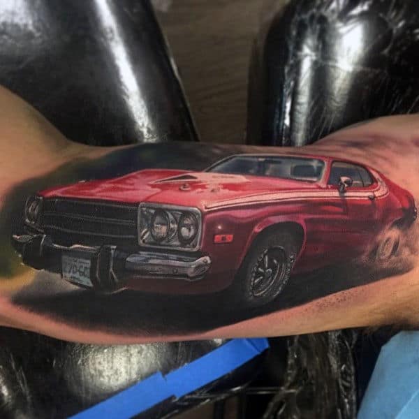 A realistic tattoo of a vintage red muscle car on bicep, showcasing detailed shadowing and highlights