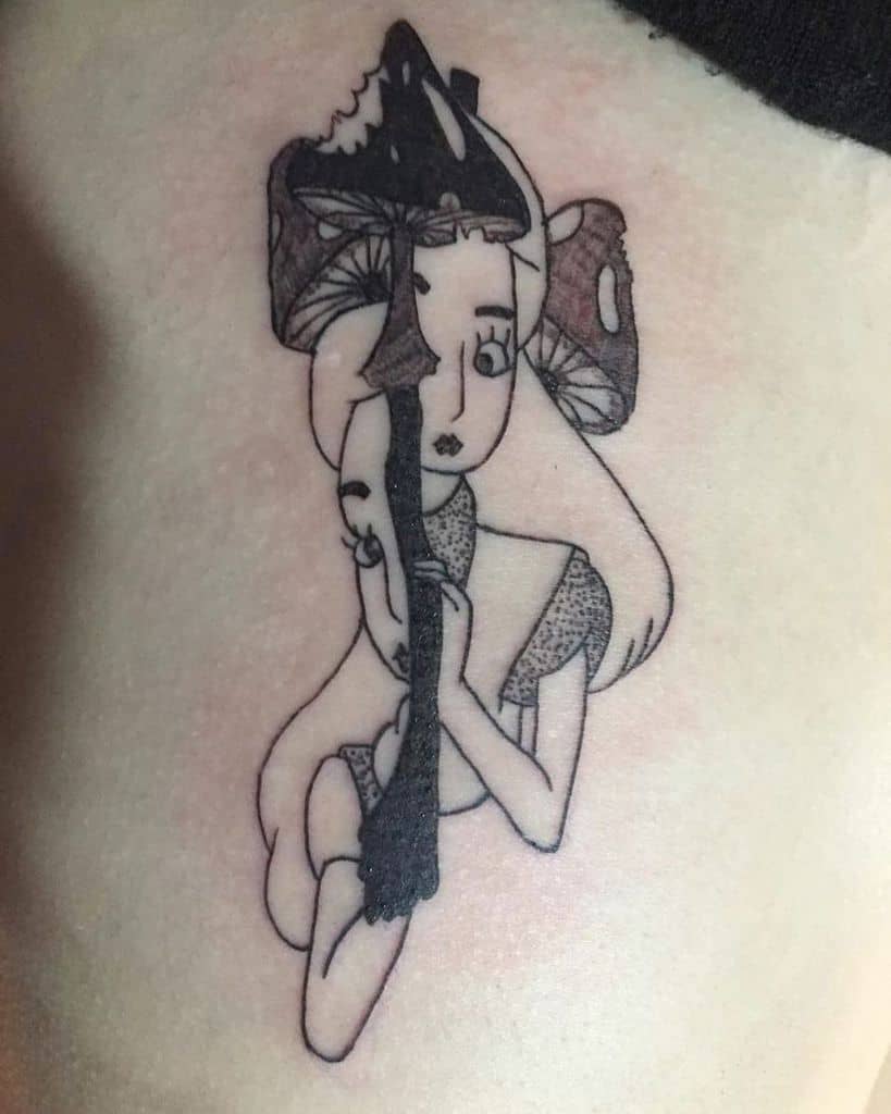 A two half tattoo of Alice from Alice in Wonderland, with mushrooms growing from her hat and its stem in the middle