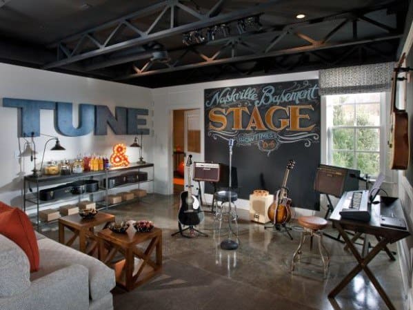 Music-themed man cave with guitars, amps, and "Nashville Basement Stage" chalkboard, cozy seating area included