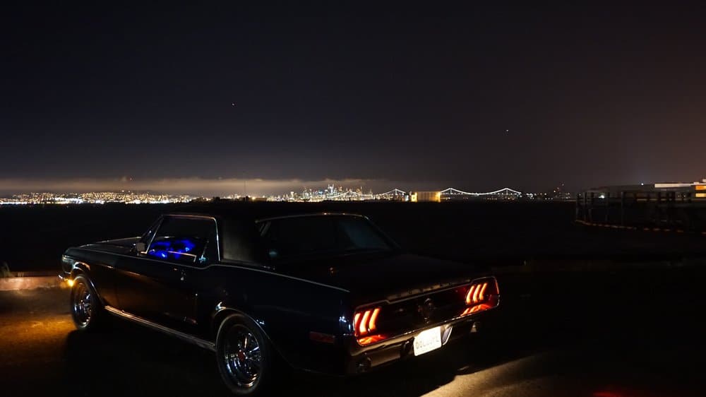 mustang sits parked at night, overlooking the city skyline