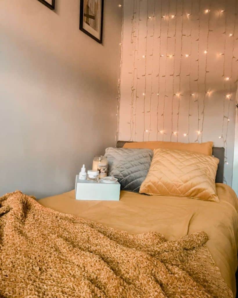 Cozy bedroom with a yellow bed, decorative pillows, and soft ambient lighting from string lights above