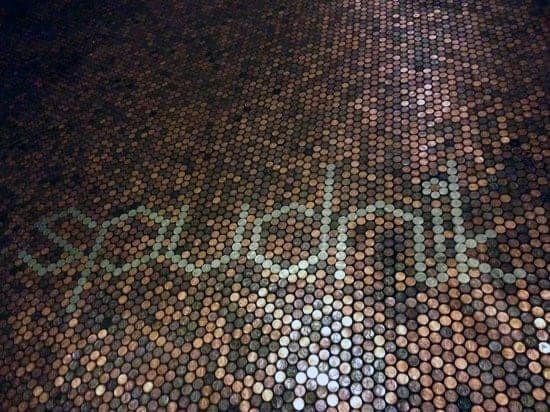 Penny floor featuring the word "spudnik" crafted with contrasting coin shades.