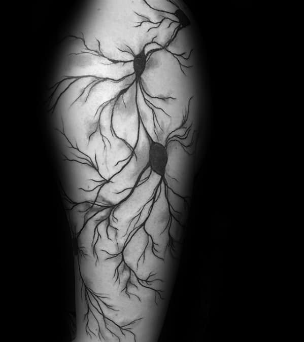 Black and grey tattoo of multiple interconnected neurons with shaded cell bodies and branching dendrites flowing down the upper arm.