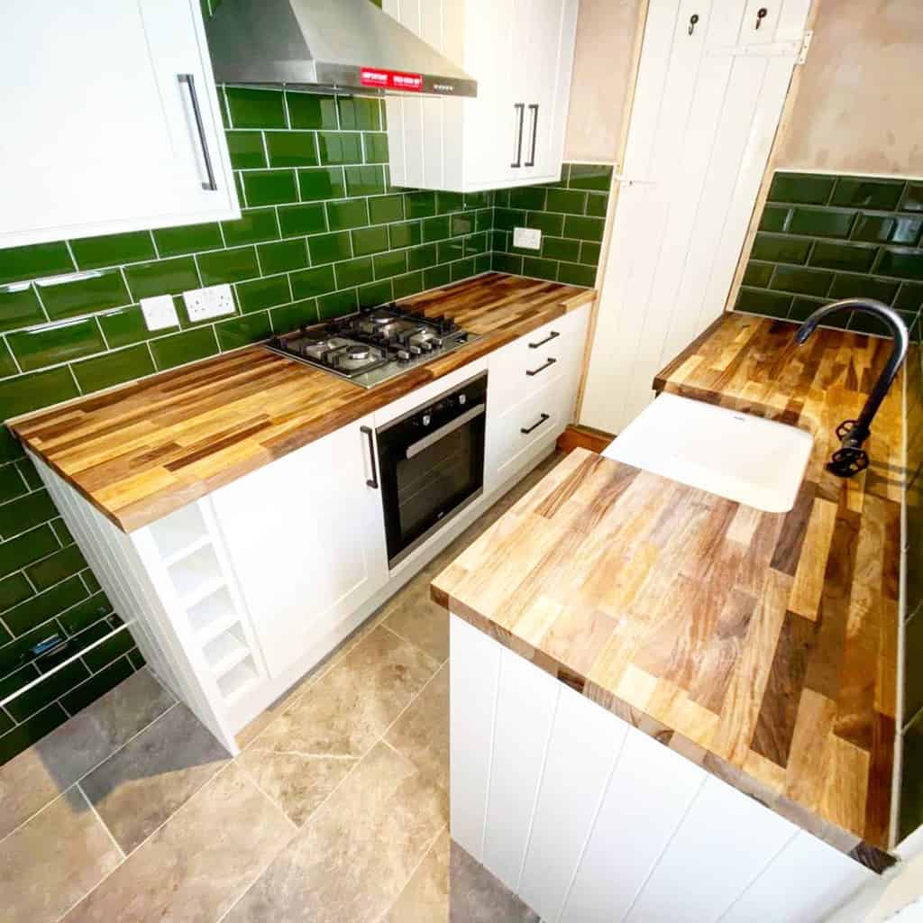narrow galley kitchen green wall tiles wood countertops white cabinets