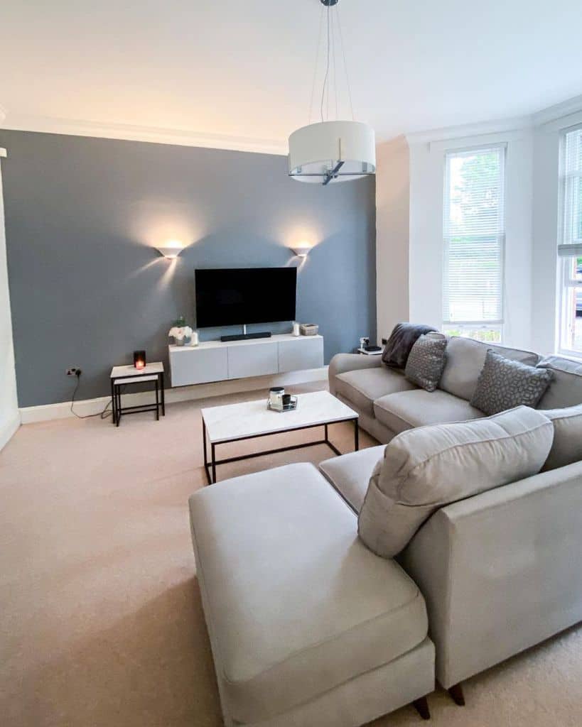 minimalist living room with blue accent wall and gray sofa 