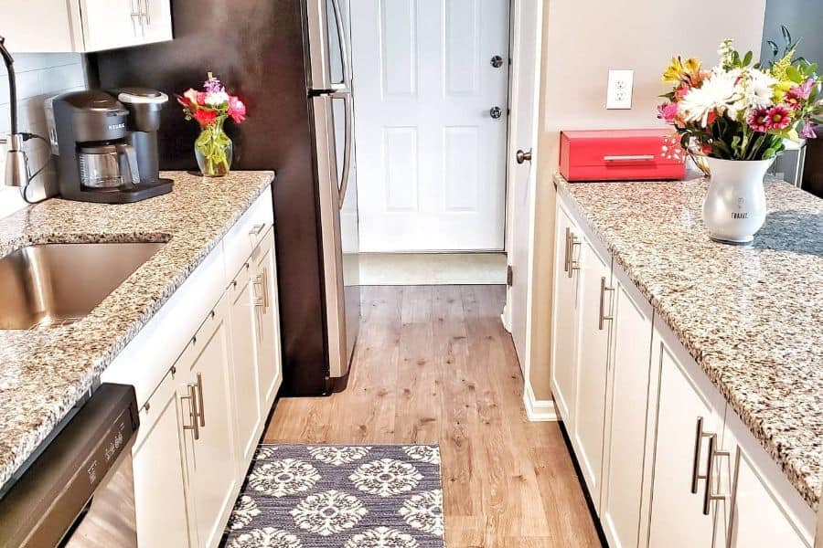 small galley kitchen with white cabinets and granite countertop