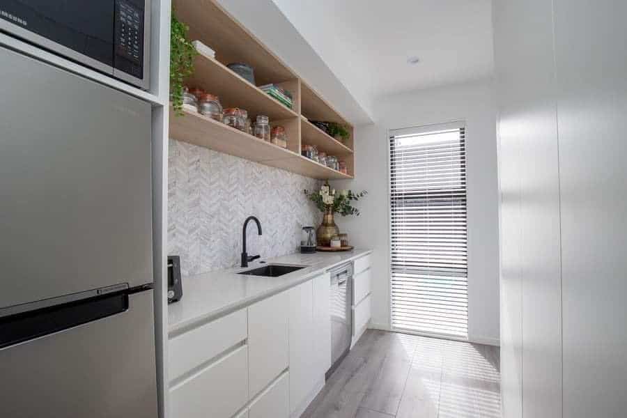 narrow small kitchen with white cabinets and wood wall shelves