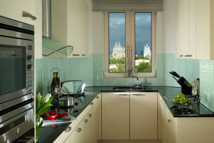 small narrow kitchen with white cabinets and green tile backsplash
