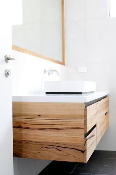 Floating natural wood vanity with white countertop and vessel sink.