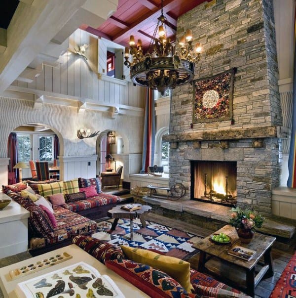 Eclectic living room with a tall stone fireplace, colorful textiles, and rustic wood accents.