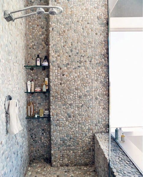 Stone-tiled shower with glass shelves, towel on hook, and sleek floor