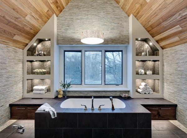 Modern bathroom with vaulted wood ceiling, built-in bathtub, and recessed shelving with lighting.