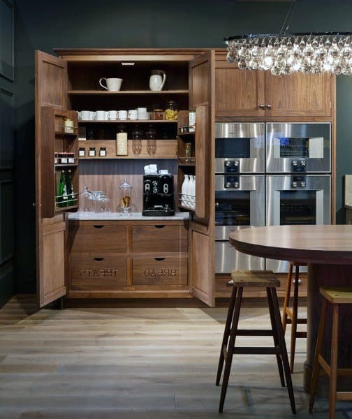 Built-in coffee bar with natural wood cabinets, open shelves, espresso machine, and glassware.