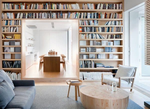 Modern living room with a wall-to-wall bookshelf, books, and wooden furniture