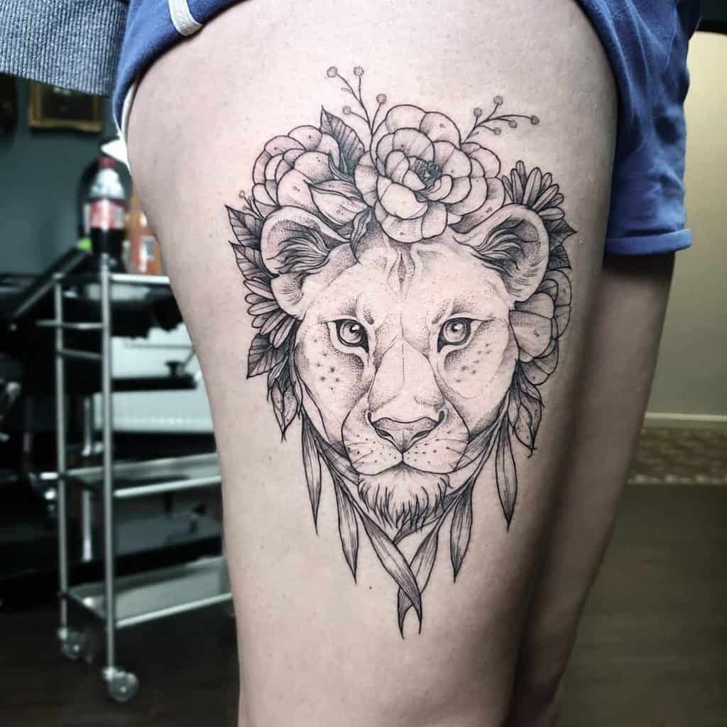 Black and grey lioness thigh tattoo with floral crown and delicate linework, blending strength and femininity in a detailed design.