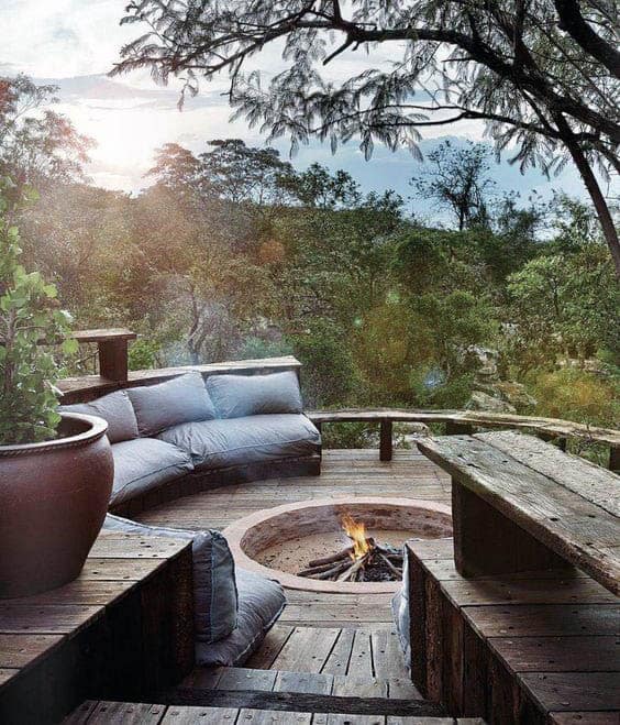 Cozy outdoor seating area with circular fire pit surrounded by nature and trees