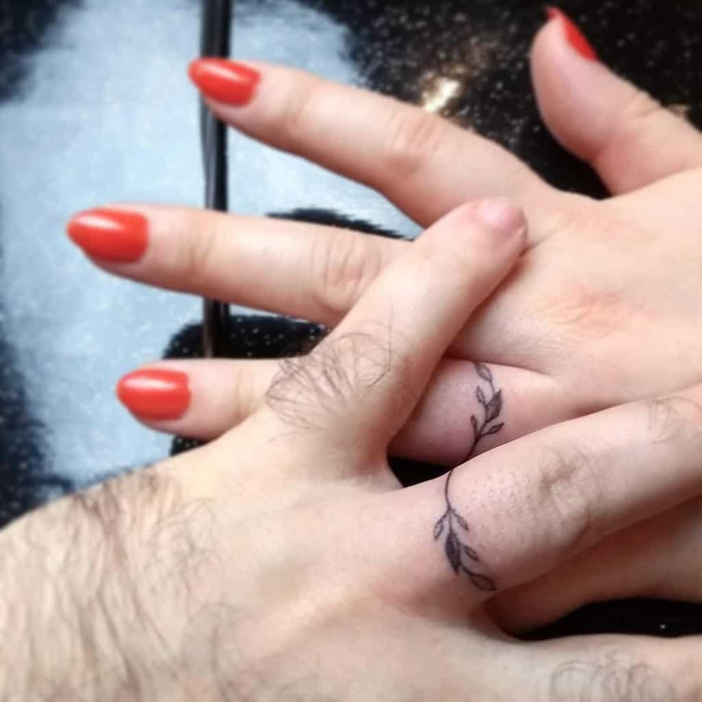 Matching minimalist leaf wedding ring tattoos, symbolizing nature, growth, and a deep connection between the two individuals