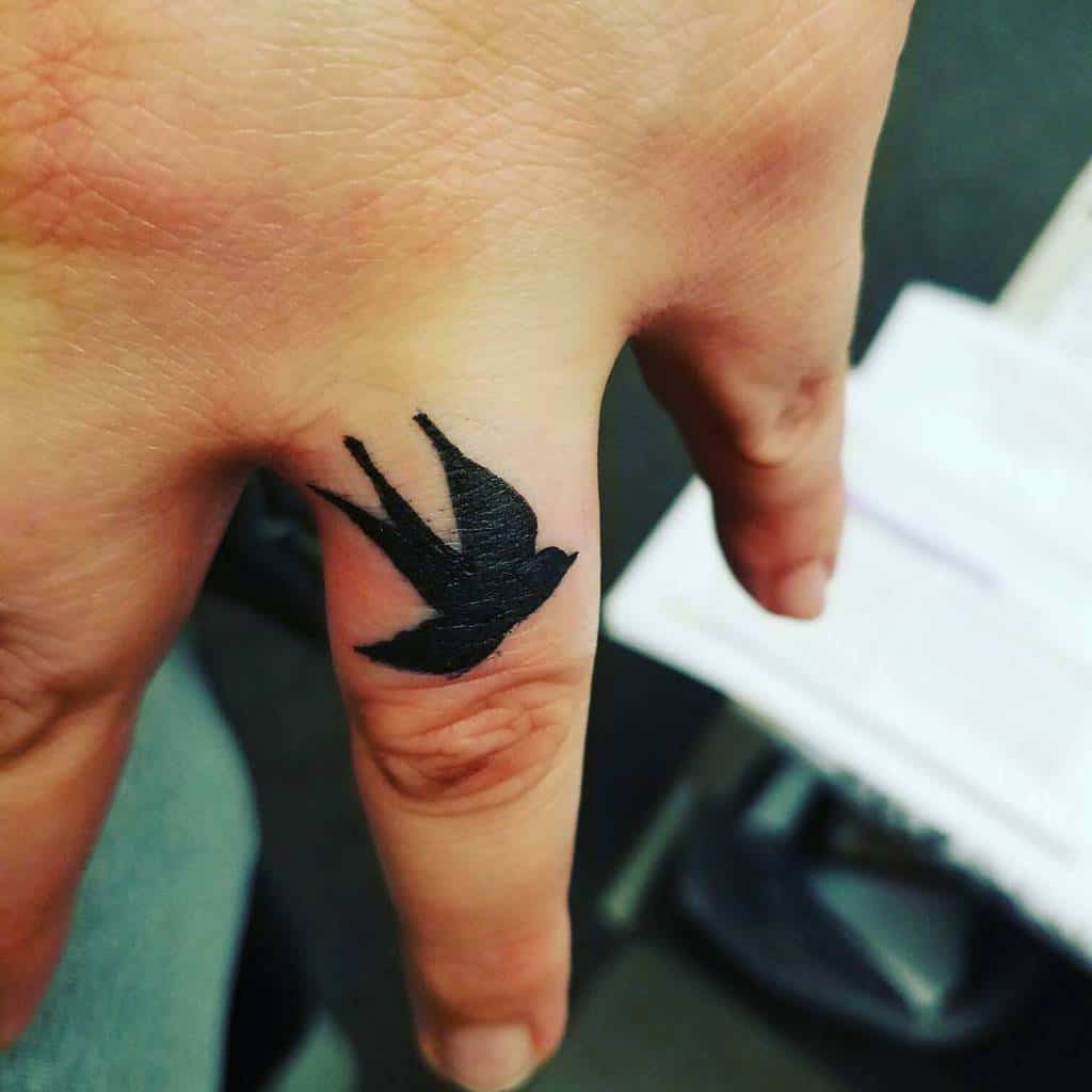 A wedding ring tattoo of a flying bird, symbolizing freedom, movement, or a new beginning