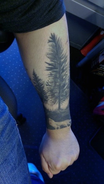 Forearm tattoo of trees and mountains in grayscale