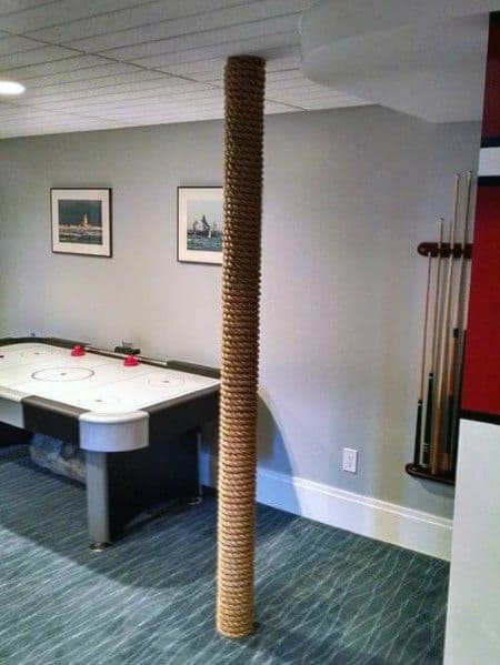 Basement with pole wrapped in nautical rope, air hockey table, and pool cue rack.