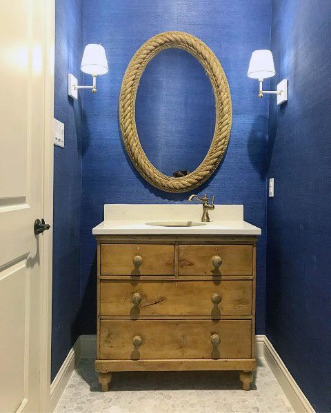 Rustic blue bathroom with a rope-framed mirror and wooden vanity.